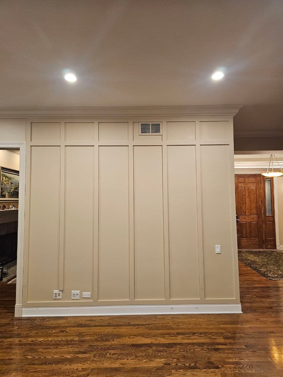 Cream board & batten accent wall with crown molding in an open living area