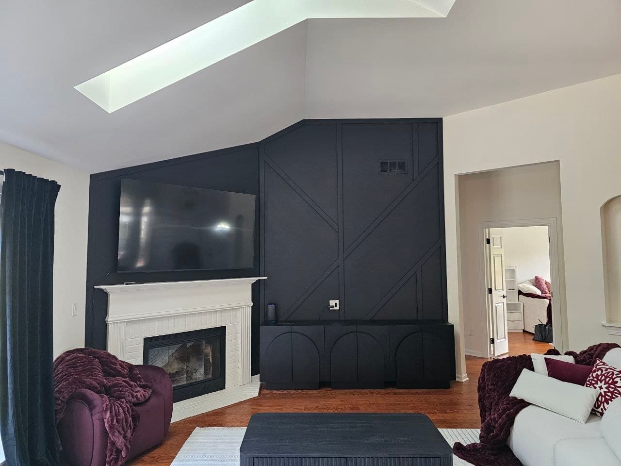 Black herringbone accent wall with a white fireplace mantle and built-in cabinet