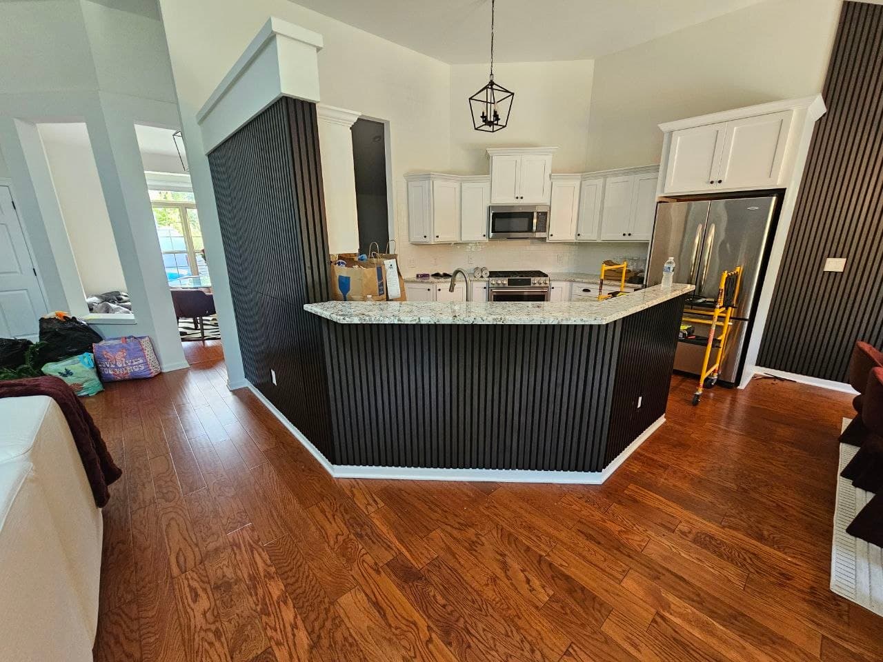 Black wood slat paneling wrapping a kitchen island and peninsula wall