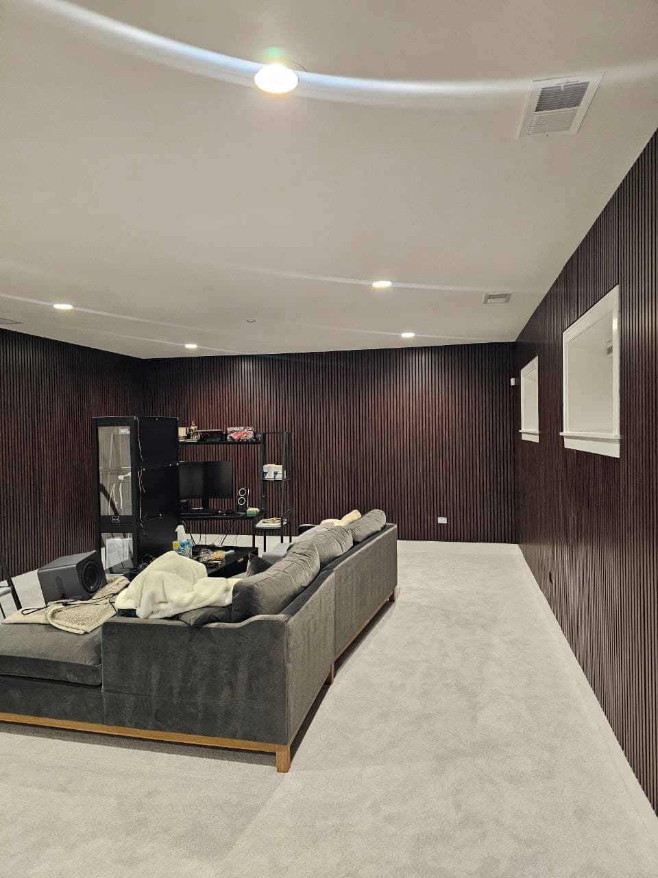 Dark walnut wood slat paneling wrapping a full home theater room