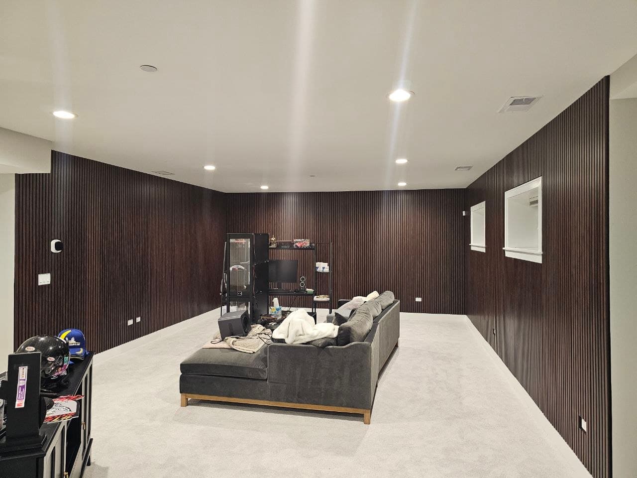 Dark walnut wood slat paneling wrapping two walls of an empty home theater room